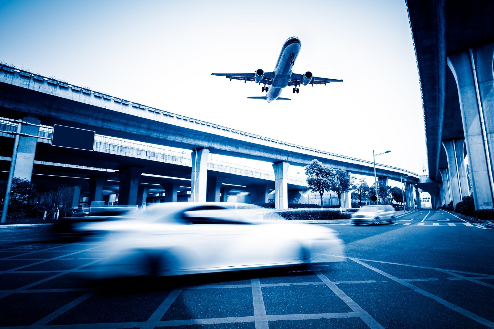 blurred-street-scene-in-city-with-a-plane-flying-over
